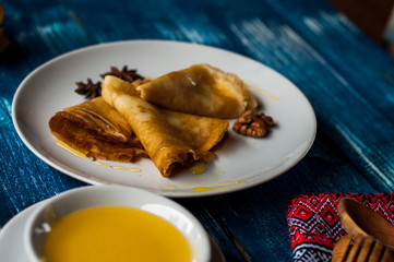 pancakes with honey syrup on a white plate. traditional crepe for pancake week or Shrovetide. crepes with roasted nuts