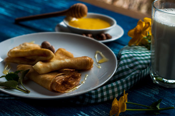 pancakes with honey syrup on a white plate. traditional crepe for pancake week or Shrovetide. crepes with roasted nuts