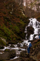 Naklejka premium Woman photographer taking photo of waterfall Travel Lifestyle adventure concept active vacations into the wild harmony with nature