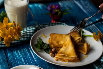 pancakes with honey syrup on a white plate. traditional crepe for pancake week or Shrovetide. crepes with roasted nuts