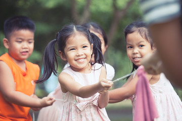 Asian children having fun to play tug-of-war with rope together in the park in vintage color tone
