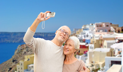 senior couple with camera travelling in santorini