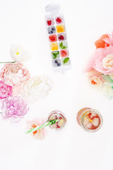 top view of fruity ice cubes with flowers and refreshing cocktails isolated ob white