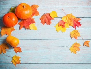 autumn leaves and pumpkins on blue wooden background