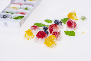 close up of ice cubes with fruits and berries isolated on white