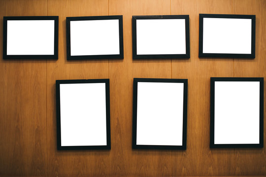 Many black frames with white background hang on wooden walls in the restaurant.