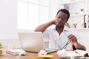 Overworked african-american employee in office, work with laptop