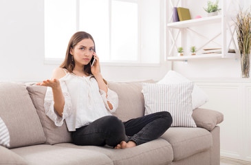 Young worried woman talking on cellphone