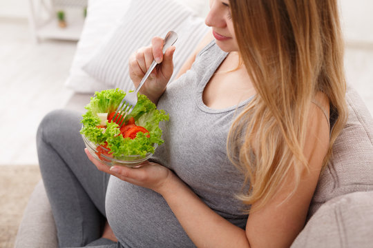 Young pregnant woman eating fresh green salad