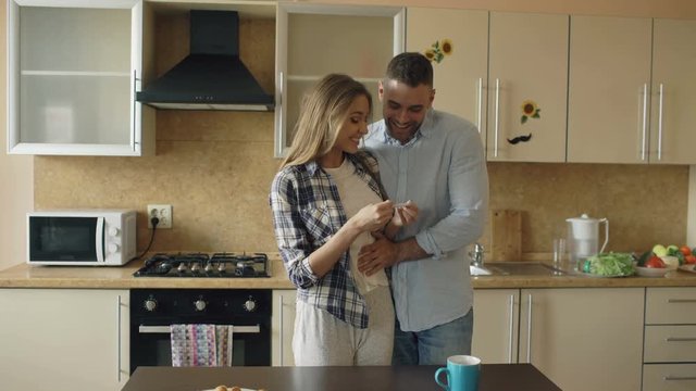 Attractive girl shows pregnancy test result to her boyfriend and surpise him at the kitchen