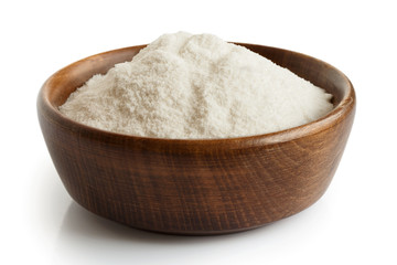 White rice flour in dark wooden bowl isolated on white. 