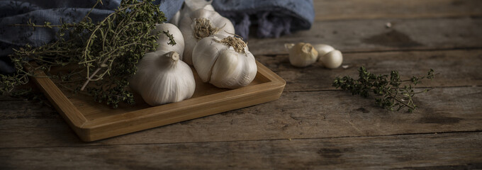 garlic and kitchen herbs on wooden table