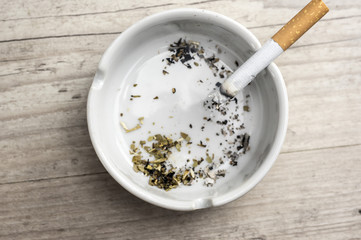 Lit cigarette burning in ashtray close up