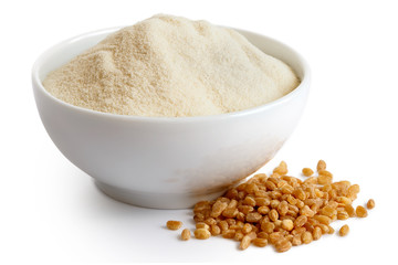 White flour in white ceramic bowl isolated on white. Spilled spelt groats.