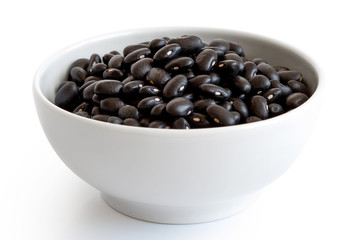 Dry black beans in white ceranic bowl isolated on white.
