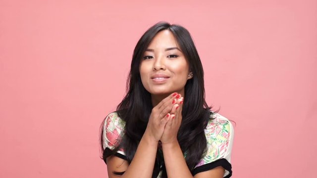 Young asian woman blowing kisses over pink background