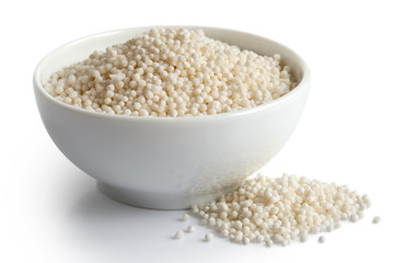 Dry tapioca pearls in white ceramic dish isolated on white. Spilled tapioca.