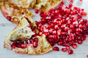 Pomegranate peel and seeds over white wooden background.