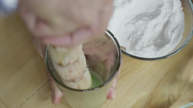 Overhead shot of a bartender using a piece of sugar cane to muddle a cocktail. Shot with a RED Dragon digital cinema camera.