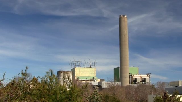 Cape cod canal power plant against blue sky and wispy clouds with trees in foreground.  Zoom in.