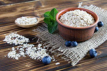 Oat flakes and blueberries on the brown wooden background