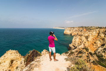 Man in end of the rock near atlantic ocean speak on phone on  summer sunny days