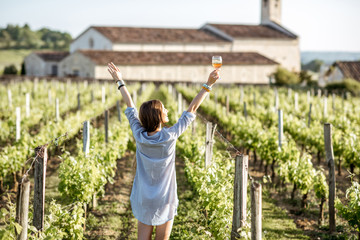 Young woman with glass of wine enjoying beautiful sunset view on the vineyard in Bordeaux region in...