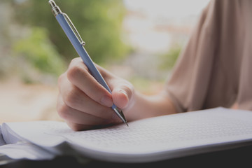 Woman sitting and holding a blue pencil and doing an exam