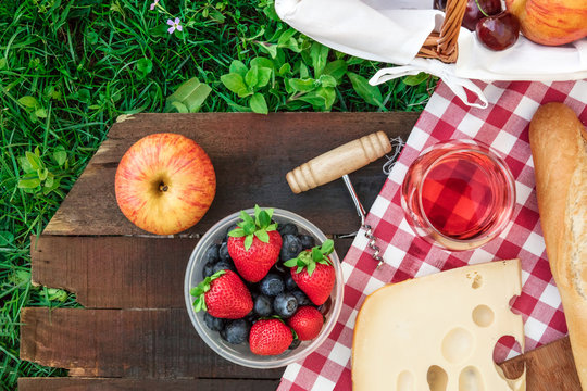 Picnic food and rose wine on wooden board with copyspace