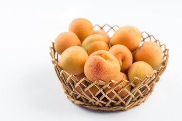 Fresh apricot in the wicker bowl above white background.