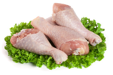 Three raw chicken drumsticks with lettuce leaf isolated on white background