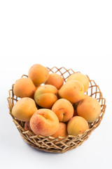 Fresh apricot in the wicker bowl above white background.