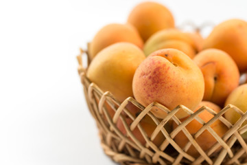 Fresh apricot in the wicker bowl above white background.