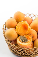 Fresh apricot in the wicker bowl above white background.