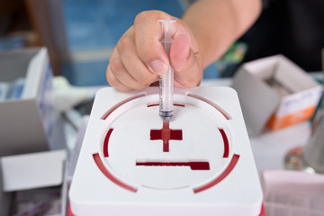 Medicine worker disposing medical waste into plastic containers ,injection needle used and leave on...