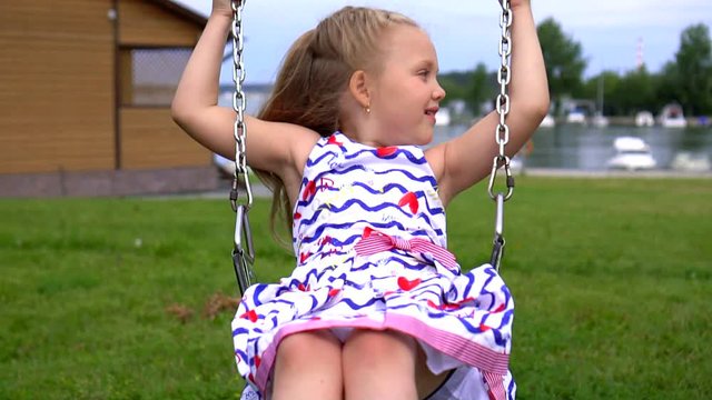 The little girl shakes on a swing in the park