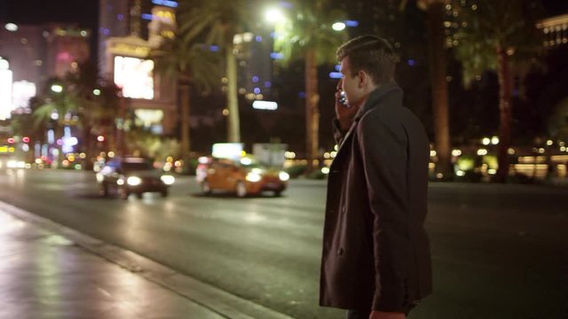 Young tourist is walking in Vegas at night and talking over his cellphone