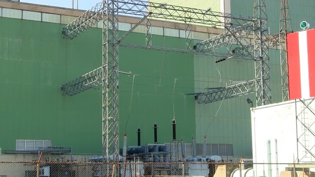 Power plant output transformers, isolators, electrodes behind barbed wire fence.  Slow zoom in