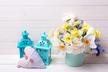 Muscaries and yellow narcissus flowers in vase, heart  and two lanterns  on  wooden background.