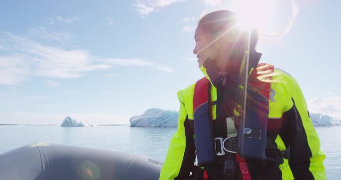 Tourist on Iceland Jokulsarlon Glacial Lagoon glacier lake in rubber boat zodiac sailing by icebergs in Vatnajokull National Park, Iceland. Happy woman enjoying adventure travel on Iceland. RED EPIC.