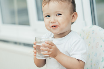 A boy drinks water in the kitchen