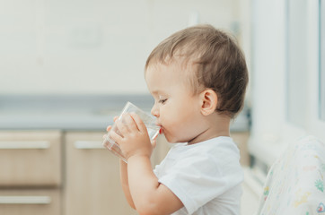 A boy drinks water in the kitchen
