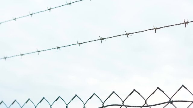 Close up of barbed wire fence surrounding electricity power station in remote industrial area, 4k handheld panning down.