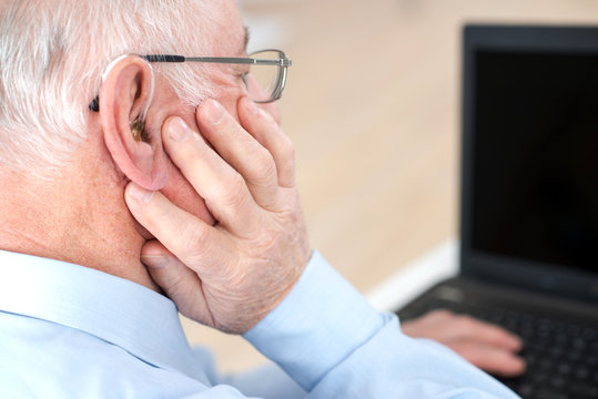 Rear View Of Elderly Man Using Laptop