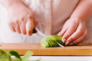 Woman's hand cutting avocado.