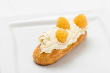 Eclair with vanilla cream and raspberries