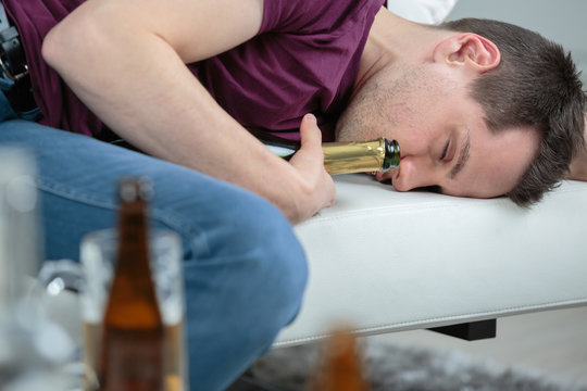 Man fallen asleep holding alcohol bottle