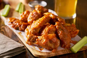  sauced buffalo chicken wings on wooden board with celery © Joshua Resnick