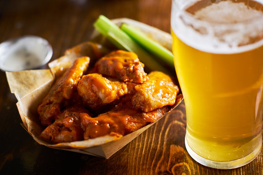 beer and hot buffalo chicken wings in tray with celery