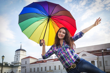 As if flying. Beautiful Caucasian girl. In his hand a colorful umbrella. Maybe it will rain.